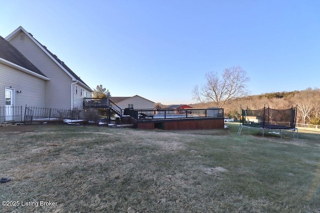 view of yard featuring a wooden deck and a trampoline