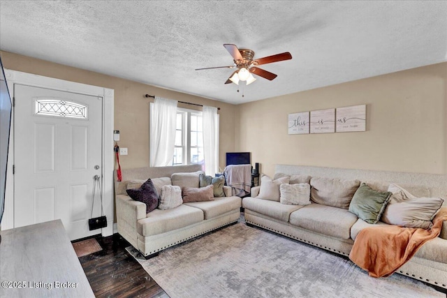 living room featuring dark hardwood / wood-style flooring, ceiling fan, and a textured ceiling