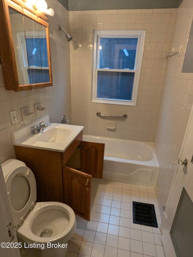 full bathroom featuring tile walls, tiled shower / bath combo, vanity, toilet, and tile patterned floors