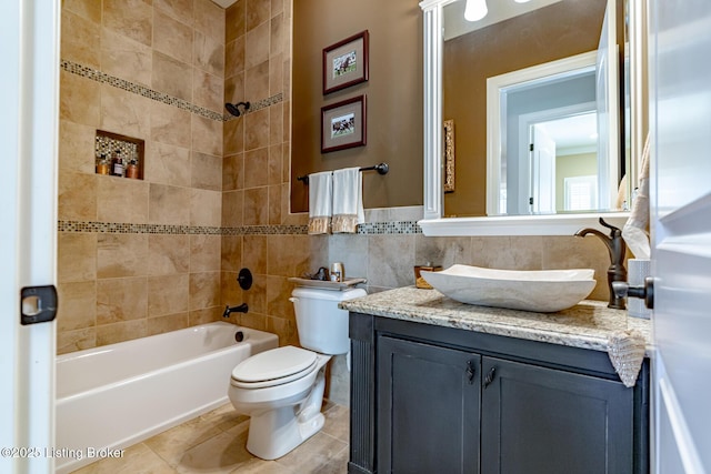 full bathroom with tile walls, tile patterned flooring, vanity, toilet, and tiled shower / bath