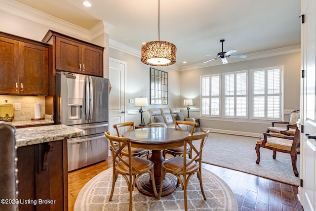 kitchen featuring light hardwood / wood-style flooring, stainless steel fridge, backsplash, ornamental molding, and light stone countertops