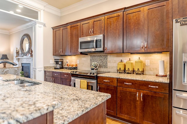 kitchen with ornamental molding, appliances with stainless steel finishes, sink, and light stone counters