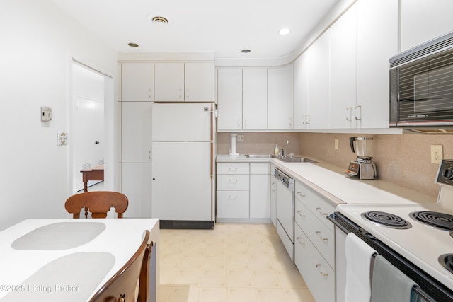 kitchen featuring tasteful backsplash, sink, white cabinets, and white appliances