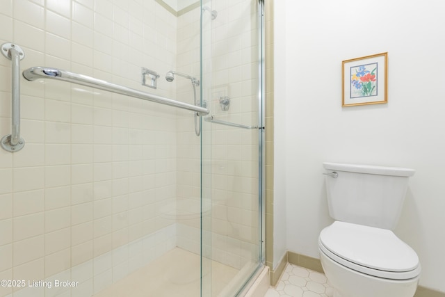 bathroom featuring a shower with door and toilet