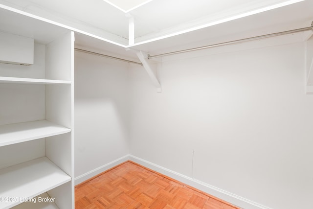 spacious closet featuring a wall mounted air conditioner and parquet flooring