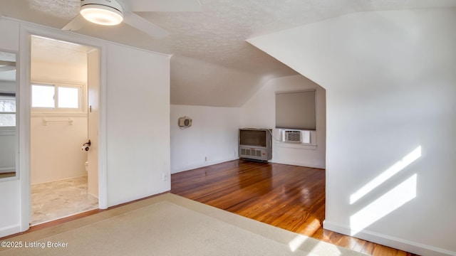 bonus room with hardwood / wood-style floors, vaulted ceiling, and a textured ceiling