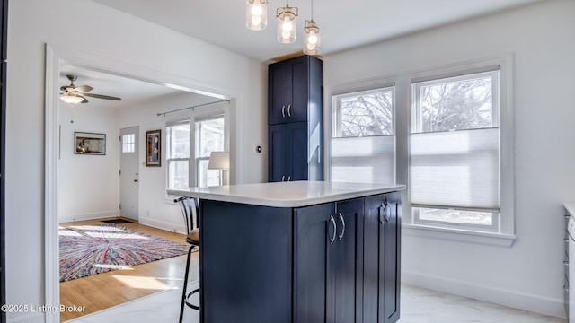 kitchen with a kitchen breakfast bar, decorative light fixtures, blue cabinets, ceiling fan, and a center island