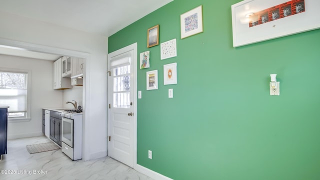 kitchen with white cabinets, a wealth of natural light, sink, and white range with gas cooktop