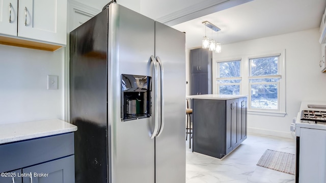 kitchen with decorative light fixtures, gas range gas stove, white cabinetry, and stainless steel fridge