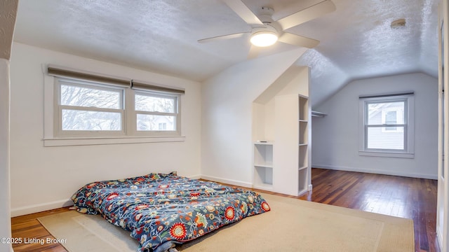 bedroom featuring dark hardwood / wood-style flooring, vaulted ceiling, and a textured ceiling