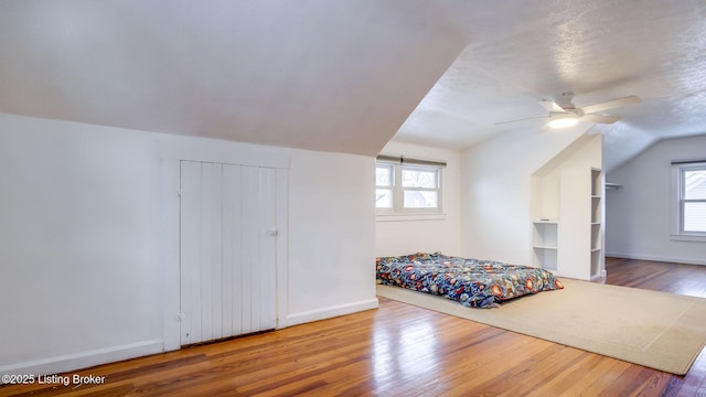 bedroom featuring ceiling fan, vaulted ceiling, multiple windows, and hardwood / wood-style floors