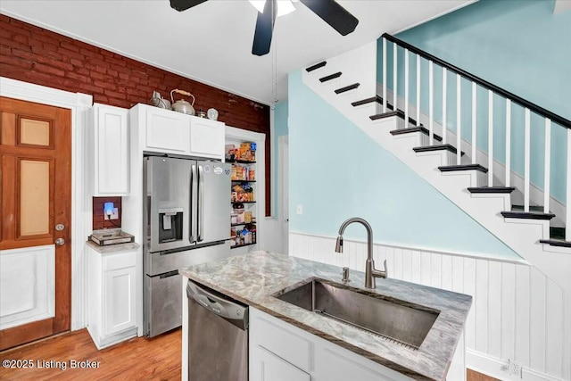 kitchen with sink, white cabinets, stainless steel appliances, light stone countertops, and light hardwood / wood-style flooring