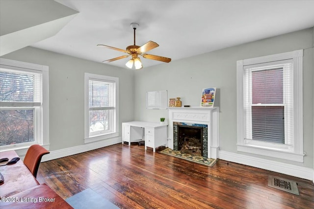 living room with ceiling fan, a fireplace, and dark hardwood / wood-style flooring