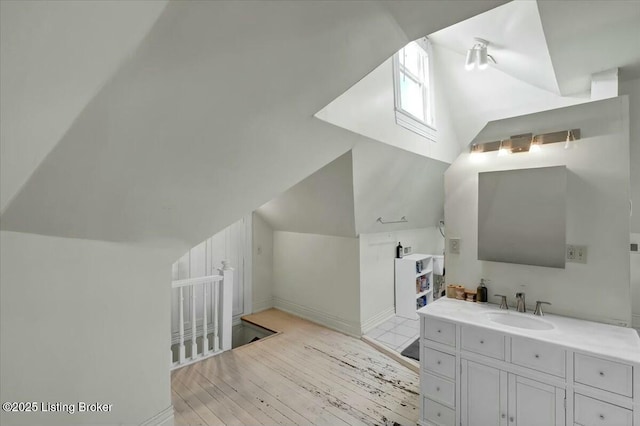 bathroom with sink, vaulted ceiling, and wood-type flooring