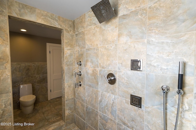 bathroom with tiled shower, toilet, and tile walls