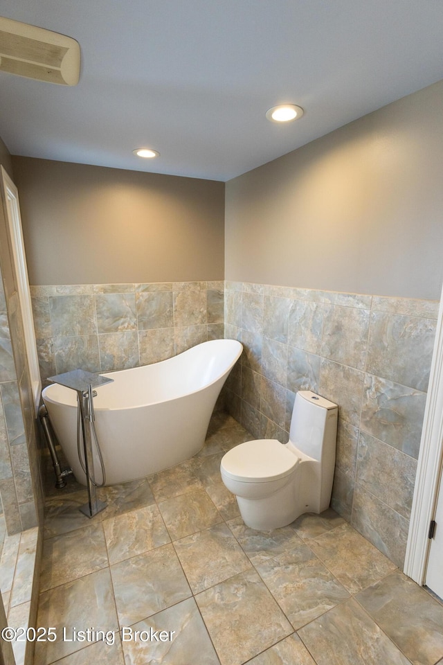 bathroom with toilet, a bathtub, and tile walls