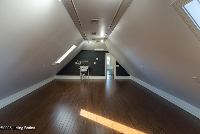 bonus room featuring vaulted ceiling with skylight and dark hardwood / wood-style flooring