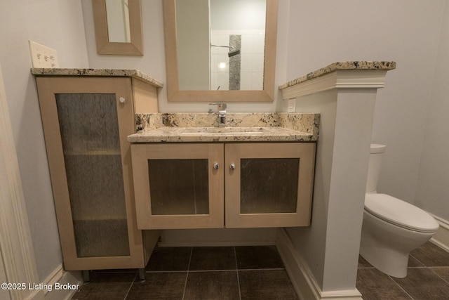 bathroom with vanity, tile patterned flooring, toilet, and walk in shower