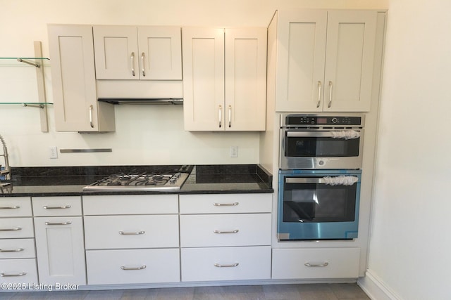 kitchen featuring white cabinetry, stainless steel appliances, and dark stone counters