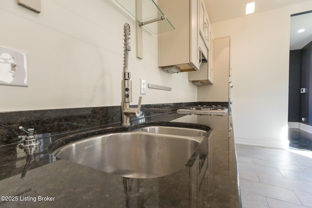 kitchen featuring dark stone countertops, sink, and stainless steel gas cooktop