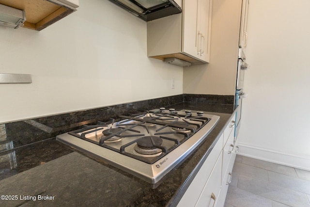 kitchen featuring white cabinetry, gas cooktop, dark stone counters, and light tile patterned floors