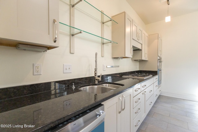 kitchen featuring dark stone counters, stainless steel appliances, sink, and white cabinets