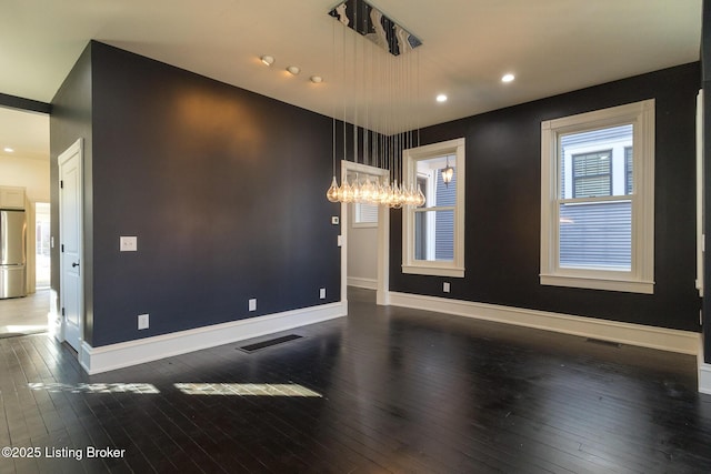 empty room featuring dark hardwood / wood-style flooring and a notable chandelier