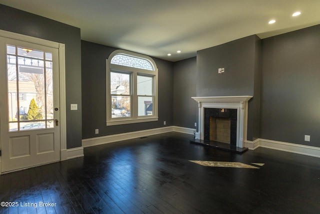 unfurnished living room featuring a premium fireplace and dark wood-type flooring