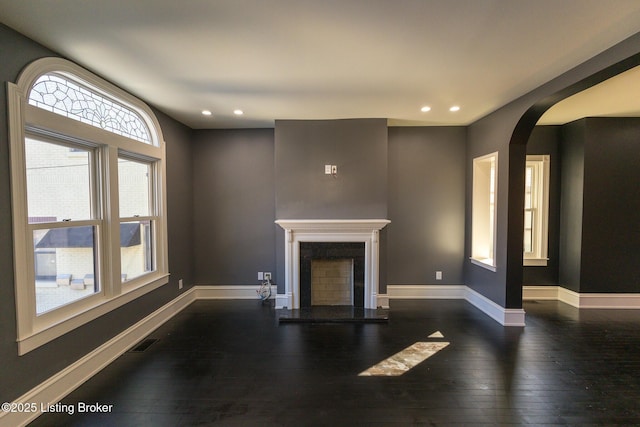 unfurnished living room featuring dark wood-type flooring and a premium fireplace