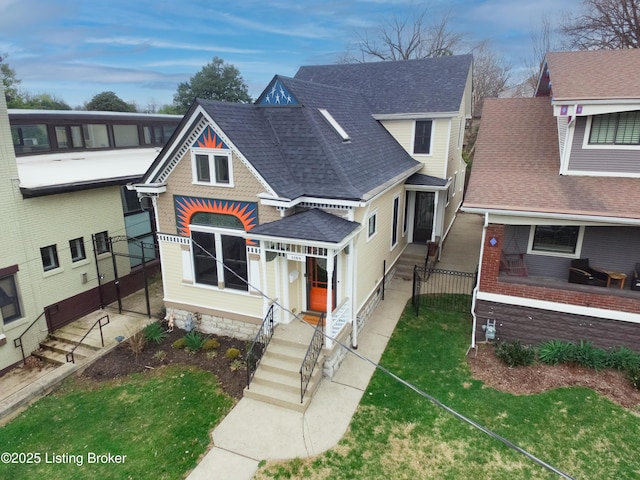 view of front of house featuring a front yard, fence, entry steps, and roof with shingles