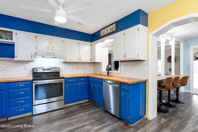 kitchen with sink, dark wood-type flooring, appliances with stainless steel finishes, white cabinets, and wood counters