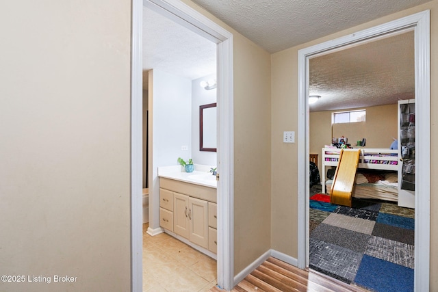 corridor featuring sink and a textured ceiling