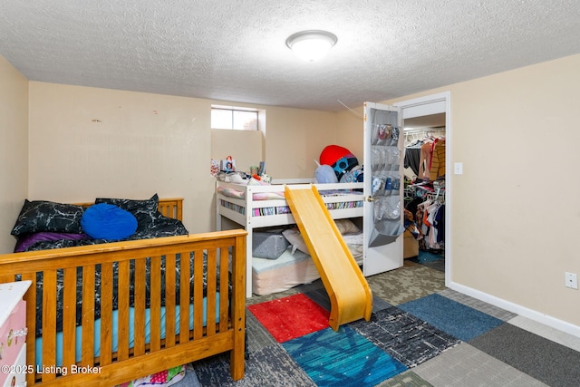 bedroom with a walk in closet, a closet, a textured ceiling, and carpet flooring