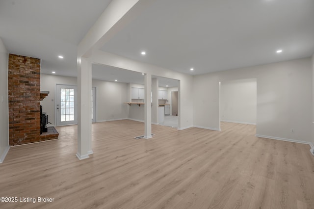 basement featuring a brick fireplace and light hardwood / wood-style flooring