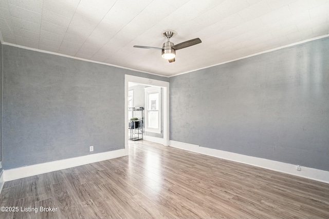 empty room featuring hardwood / wood-style flooring, ornamental molding, and ceiling fan