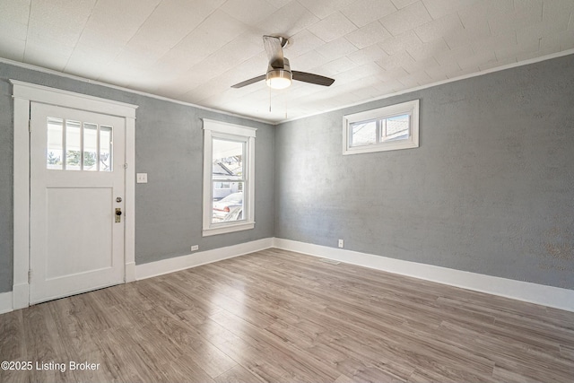 entrance foyer featuring ceiling fan, ornamental molding, wood-type flooring, and a wealth of natural light