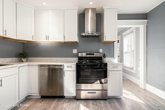 kitchen featuring white cabinets, wall chimney exhaust hood, and appliances with stainless steel finishes