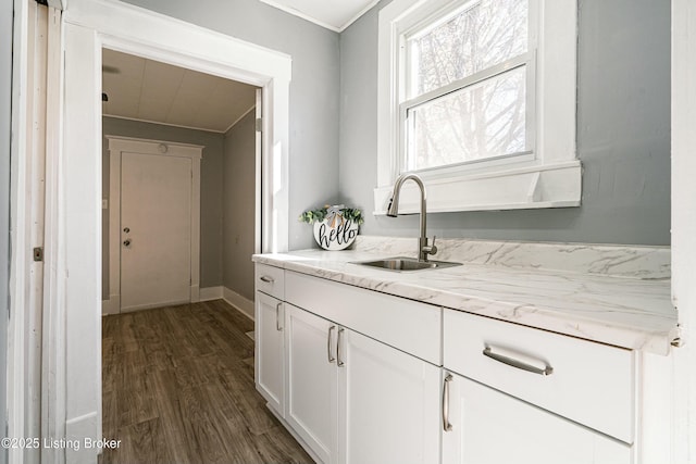 kitchen featuring light stone counters, dark hardwood / wood-style floors, sink, and white cabinets