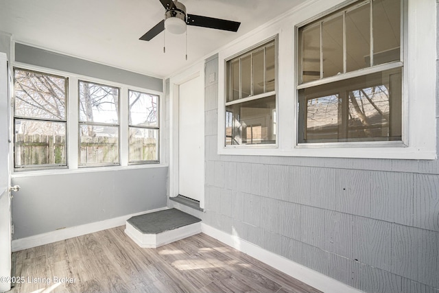 unfurnished sunroom featuring ceiling fan