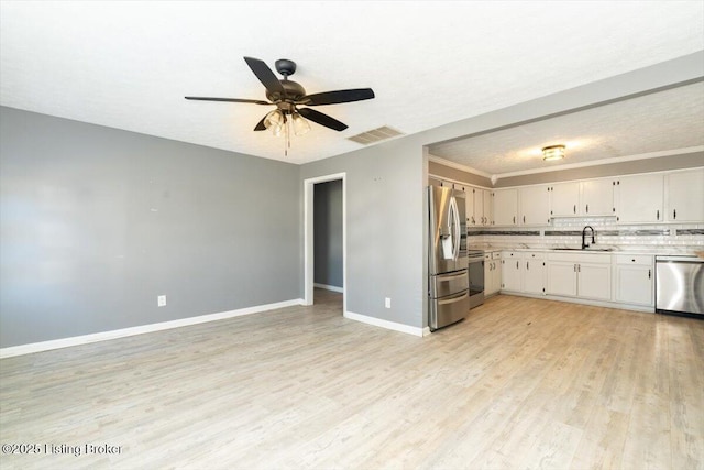 kitchen with sink, white cabinetry, stainless steel appliances, light hardwood / wood-style floors, and decorative backsplash