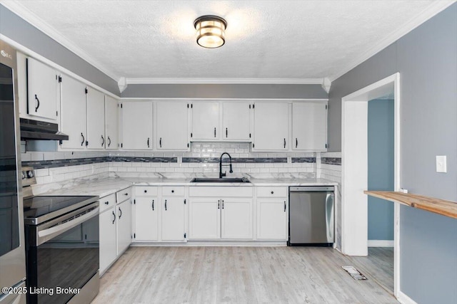 kitchen featuring appliances with stainless steel finishes, sink, white cabinets, ornamental molding, and light wood-type flooring