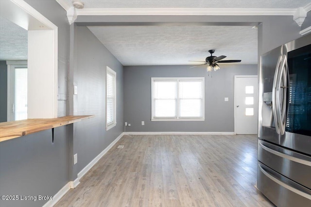 unfurnished living room with crown molding, ceiling fan, a textured ceiling, and light wood-type flooring