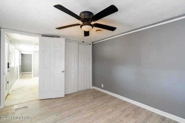 unfurnished bedroom featuring crown molding, light hardwood / wood-style floors, a closet, and a textured ceiling