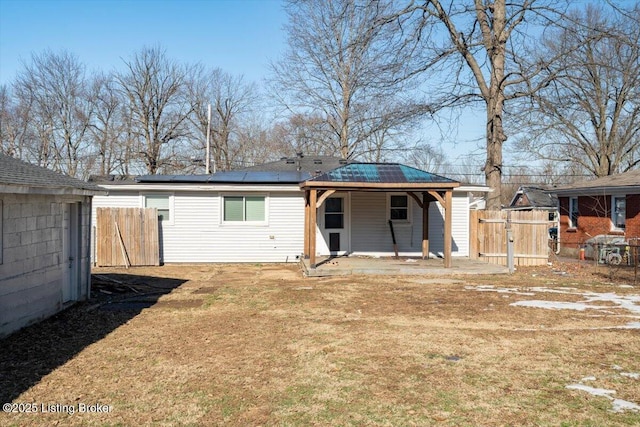 back of property featuring a yard and solar panels