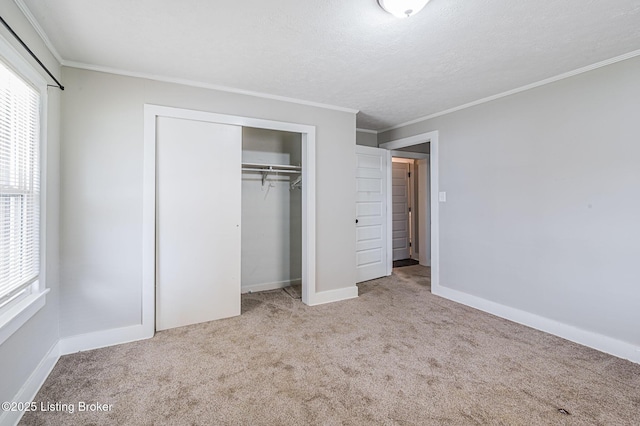 unfurnished bedroom featuring crown molding, light colored carpet, a textured ceiling, and a closet