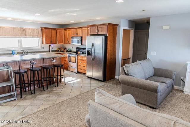 kitchen featuring stainless steel appliances, sink, a breakfast bar, and light tile patterned floors