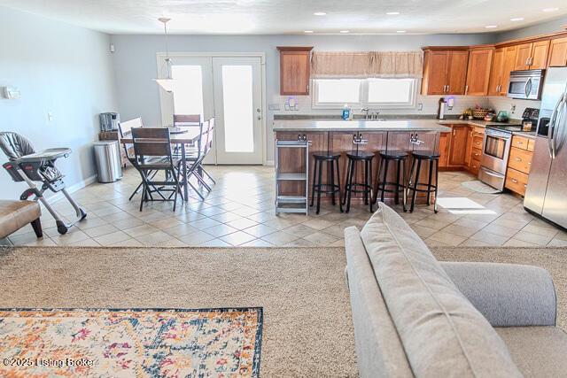 kitchen featuring stainless steel appliances, light tile patterned flooring, plenty of natural light, and a kitchen breakfast bar