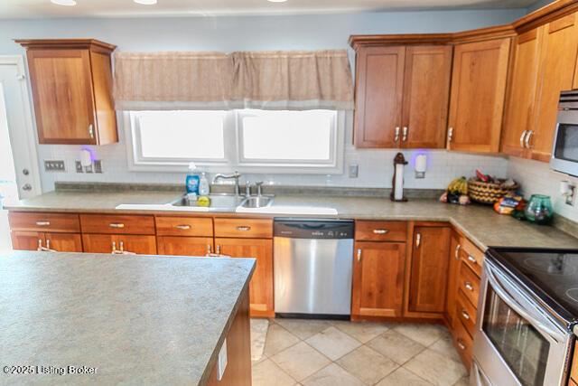 kitchen with light tile patterned flooring, appliances with stainless steel finishes, sink, and decorative backsplash