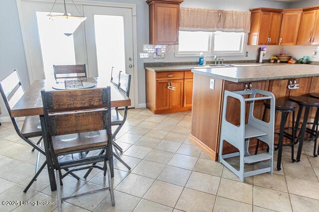 kitchen with a kitchen island, pendant lighting, sink, decorative backsplash, and light tile patterned floors