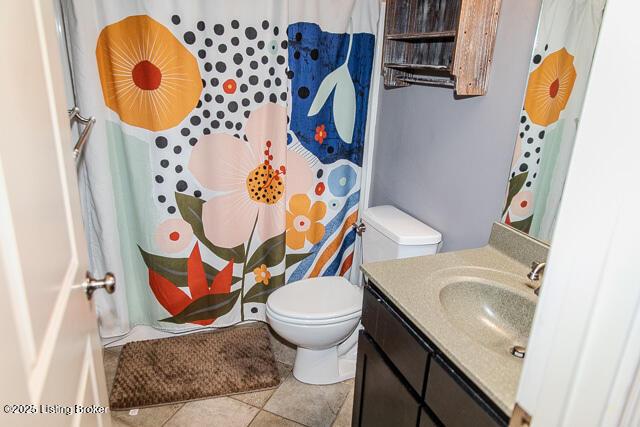 bathroom featuring tile patterned flooring, vanity, curtained shower, and toilet